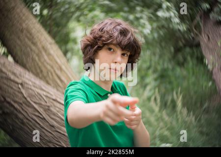 Porträt eines Jungen auf dem Hintergrund der Natur. Hand, die auf das Ziel zeigt. Stockfoto