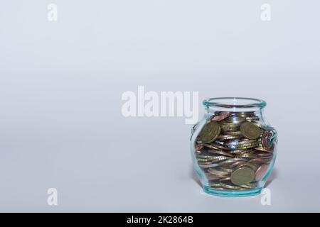 Geld in einem Glas mit vielen verschiedenen Euro-Münzen für finanzielle Unabhängigkeit mit Grau gespart Stockfoto