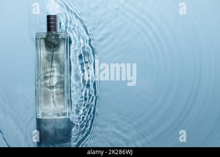 Parfümflasche auf blauem, welligem Hintergrund. Duftkonzept mit frischem Meeresduft. Rein Stockfoto