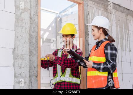 Männliche industrielle Bauarbeiter Verlegeprozess Holztür mit Maßband messen Stockfoto