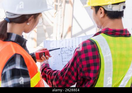 Architekt und Bauherr besprechen den Plan mit dem Bauplan des Gebäudes auf der Baustelle Stockfoto