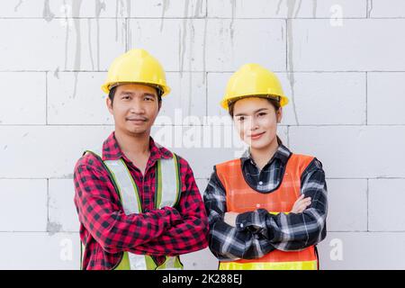 Porträt von Frau und Mann, Architekt mit Schutzhelm auf Kopf in Weste, der im Baugewerbe steht Stockfoto