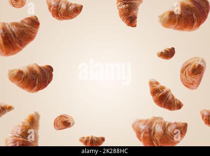 Schwebende oder fliegende Croissants auf weißem beigefarbenem Hintergrund. Schweben, Fliegenbühne Stockfoto