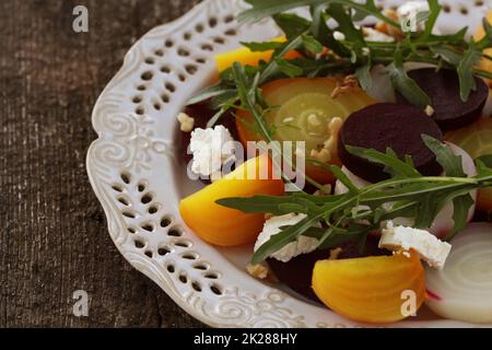 Gesunde Rüben Salat mit roten, weißen und goldenen Rüben, Rucola, Muttern, Feta Käse auf Holz- Hintergrund Stockfoto