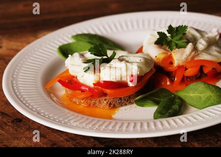 Eggs Benedict. Geröstete Muffins mit Paprika, Spinat, pochierten Eiern Stockfoto