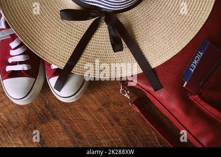 Damen Sommer-Outfit: Rote Sneakers, Rucksack, Hut . Reisehintergrund und Touristeninformation. Draufsicht Stockfoto