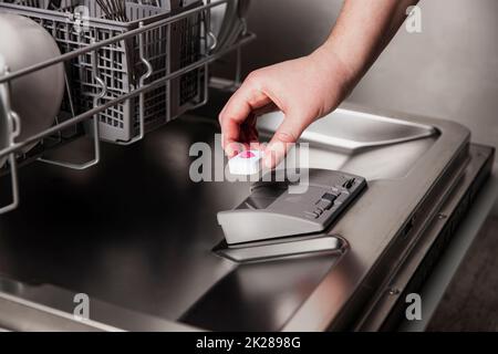 Weibliche Handeinlage für Geschirrspülmaschine in offener Spülmaschine in der Küche Stockfoto