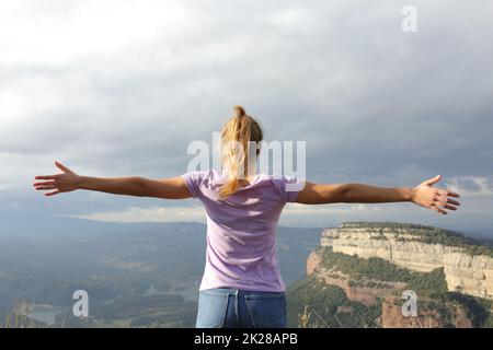 Eine Frau, die sich die Arme ausstreckt, um Urlaub in der Natur zu feiern Stockfoto