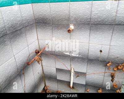 Verlassenes Haus, alte Schlussfolgerungen zur Wasserversorgung und Abwasserentsorgung im ehemaligen Badezimmer. Stockfoto