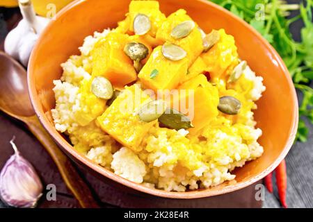 Porridge Millet mit würzigem Kürbis in Tonschüssel auf dunklem Brett Stockfoto