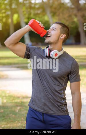 Läufer lächelnder junger lateiner trinkt Wasser im Porträtformat laufen Sporttraining Fitness-Workout Stockfoto