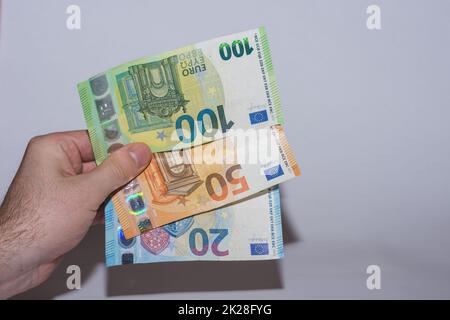 Drei graue Euro-Banknoten in einer Hand an der Seite Stockfoto