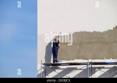 Verputzer Bauer verputzte Wand in einem Gewerbegebäude. Wor Stockfoto