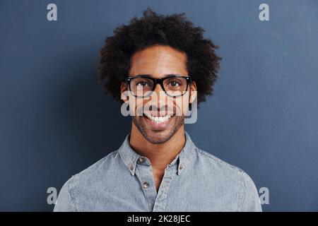 Ich lasse mich nicht von Etiketten definieren. Porträt eines hübschen jungen Mannes mit Brille auf grauem Hintergrund. Stockfoto