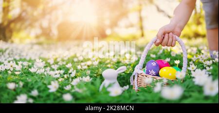 Kind hält in der Hand ein Becken mit bunten Eiern. Stockfoto