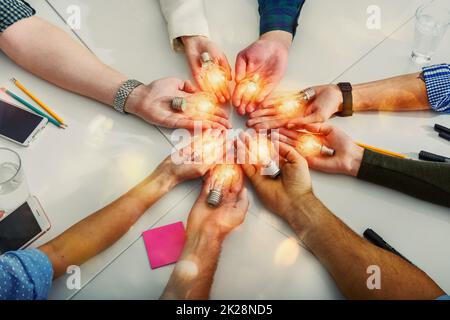 Teamwork und Brainstorming-Konzept mit Geschäftsleuten, die eine Idee mit einer Lampe teilen Stockfoto