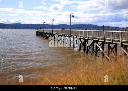 Der hölzerne Pier, der aus den Herbstbüschen auf dem Fluss kommt Stockfoto