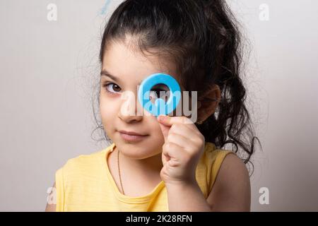 Kleines Mädchen Portrait guckt durch englischen Q Brief Stockfoto