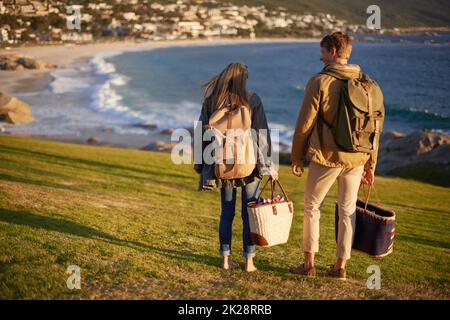 Zusammen gut stehen auf der Oberseite der Welt. Ein Paar, das auf dem Rand einer Böschung mit Blick auf das Meer steht. Stockfoto