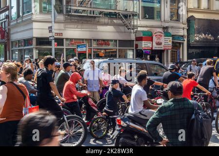 Hunderte von Menschen mit Fahrrädern und Motorrollern übernehmen die West 23. Street Road und den Bürgersteig in Chelsea in New York, während sie am Sonntag, dem 18. September 2022, in einem Paket reisen. (© Richard B. Levine) Stockfoto
