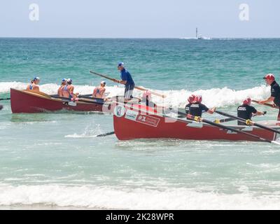 Tauranga Neuseeland - Januar 25 2009; zwei Surfboote mit weiblicher Crew und männlichem Sweep-Steering kehren zum Landrennen zurück, während die kleinen Wellen reiten Stockfoto