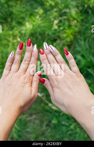 Das Mädchen zeigt eine schlechte alte Maniküre. Überwucherter Nagellack, gebrochener Nagel. Maniküre Korrektur, alte Maniküre. Nagelpflege, es ist Zeit, in den Salon zu gehen Stockfoto