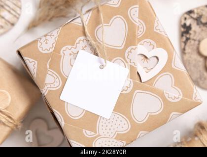 Valentinsgeschenk mit leerem Geschenkanhänger und Herzen aus der Nähe, Rustic Label Mockup Stockfoto