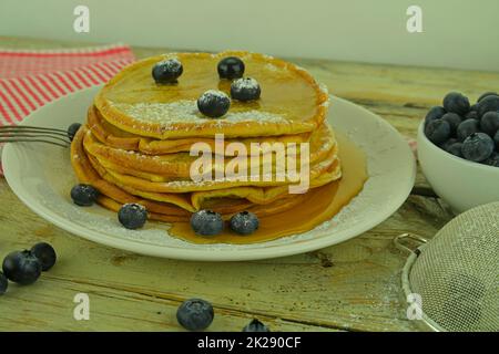 Hausgemachte amerikanische Pfannkuchen mit frischen Blaubeeren und Ahornsirup. Gesundes Frühstück. Rustikaler weißer Hintergrund. Pfannkuchen mit Beeren auf weißem Holzhintergrund. Nahaufnahme Stockfoto