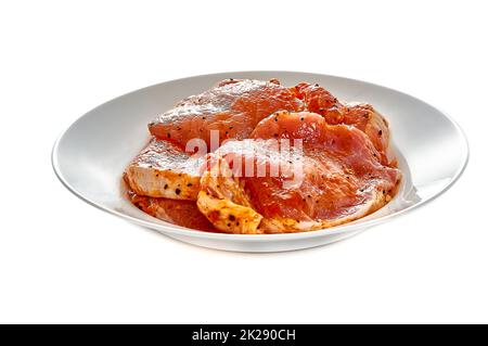 Schweinefleisch in Marinade liegt auf einem weißen Teller auf einem weißen isolierten Hintergrund Stockfoto