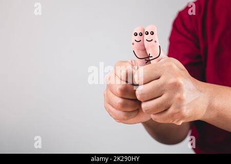 Kunst der Liebe an den Fingern. Das Zusammenziehen der Daumen der Hände. Valentinstag-Konzept mit Kopierplatz. Stockfoto