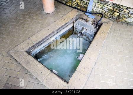 Ein kleiner Swimmingpool mit heiligen Wasser aus der Quelle. Eine Nische im Boden für die Gewinnung von Wasser aus einer Quelle Stockfoto