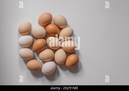 Eier in verschiedenen Brauntönen liegen dicht auf einem hellgrauen Hintergrund, Draufsicht Stockfoto