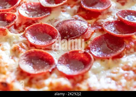 Köstliche Salami-Pizza aus nächster Nähe mit Käse und Tomatensauce als köstliche italienische Delikatesse und Diät-Fast-Food-Mittagessen für hungrige Teenager, die ungesunde nahrhafte Snacks in Stücken essen Stockfoto
