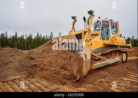 Ein gelber Traktor legt den Standort mit Sand ab Stockfoto