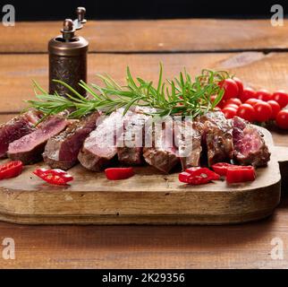 Geröstetes Stück Rinderribeye auf einem braunen Schneidebrett in Stücke geschnitten, seltener Doneness. Köstliches Steak, Nahaufnahme Stockfoto