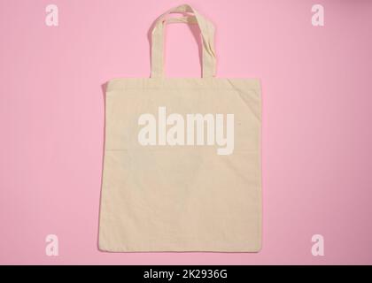 Leeres Leinen umweltfreundliche beige Leinwand-Tragetasche für Branding auf einem rosa Hintergrund. Durchsichtige wiederverwendbare Tasche für Lebensmittel, Nachbau. Flach liegend Stockfoto