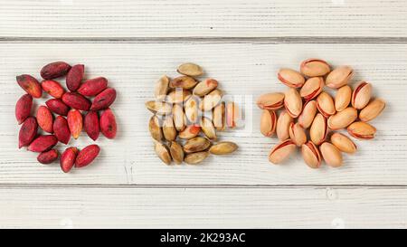 Rote türkische Pistazien auf Whiteboards. Teilweise getrocknet dunkel rosa Früchte, geschält, Nüsse sind im Inneren, und schließlich, geröstete Pistazien. Tischplatte anzeigen. Stockfoto