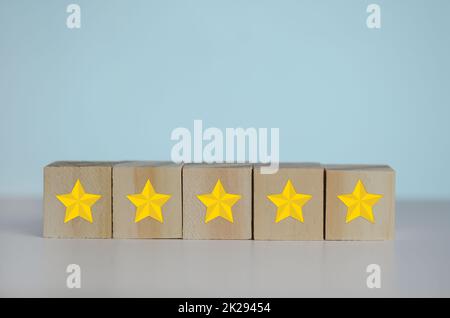 Holzwürfel mit gelbem Stern fünf Symbol auf Hintergrund und Kopierraum.Customer Experience, Zufriedenheit und beste ausgezeichnete Dienstleistungen Bewertungskonzepte. Stockfoto