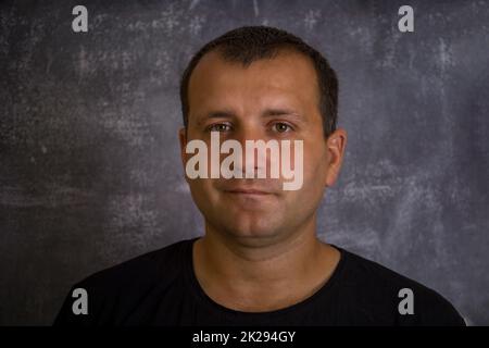 Das Gesicht eines jungen Mannes in einem schwarzen T-Shirt. Stockfoto
