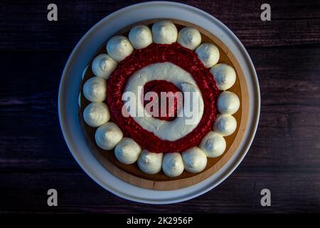 Ein Kuchen mit weißen Cremekreisen, abwechselnd mit Himbeermarmelade auf dunklem Hintergrund, Draufsicht, Nahaufnahme Stockfoto