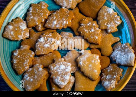 Kekse in Form von Weihnachtsbäumen liegen auf einem blauen Teller Stockfoto