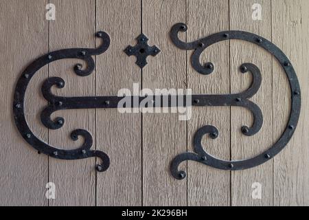 Detail einer alten roten Holztür mit schmiedeeiserner Dekoration in Form von Arabesken Stockfoto