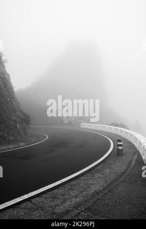 Bergstraße im Morgennebel im Norden von Teneriffa. Mirador (Aussichtsplattform) Risco Amogoje. Kanarische Inseln. Spanien. Schwarz und Weiß. Stockfoto