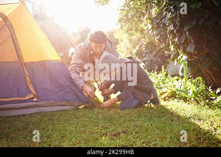 Es ist ein Durchgangsrecht. Ein Vater und sein kleiner Sohn stellen ihr Zelt auf. Stockfoto