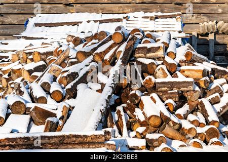 Vor kurzem gehacktes Brennholz, das sich stapelt und mit Schnee bedeckt ist Stockfoto