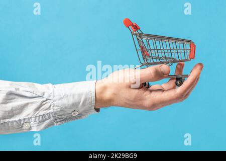 Spielzeug-Einkaufswagen in der Hand eines Geschäftsmanns Stockfoto