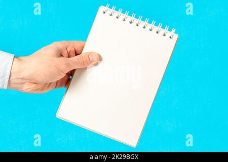 Männerhand, die ein Notizbuch mit leeren Blättern zum Schreiben hält Stockfoto