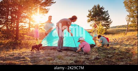 Gruppe der Menschen, die das Zelt auf der Natur in der Nähe des Meeres aufschlagen. Konzept des Familienwanderns und Kinderscout Camping. Stockfoto