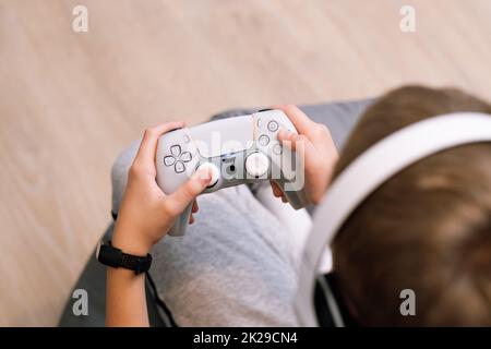 Nahaufnahme der Hände eines Jungen, der den Joystick hält. Konzept des Spielens auf der Konsole. Stockfoto