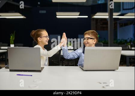 Fröhliche erfolgreiche Kinder Kollegen Kollegen geben highfive Stockfoto